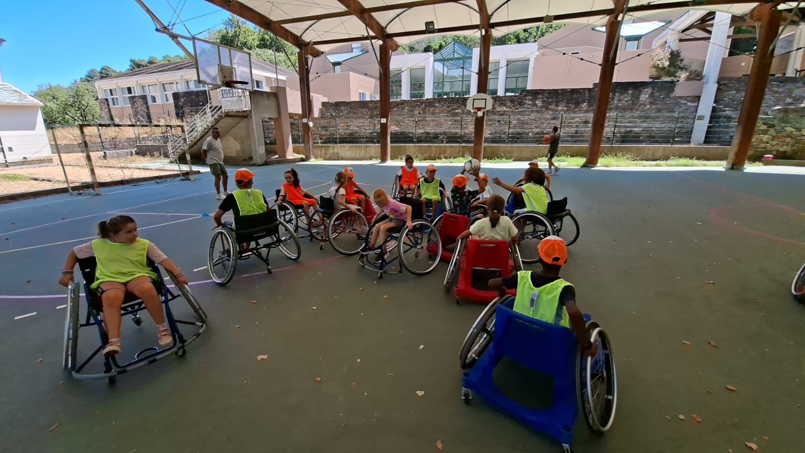 Des participants en fauteuil sportif se rassemblent sur un terrain couvert pour une séance collective.