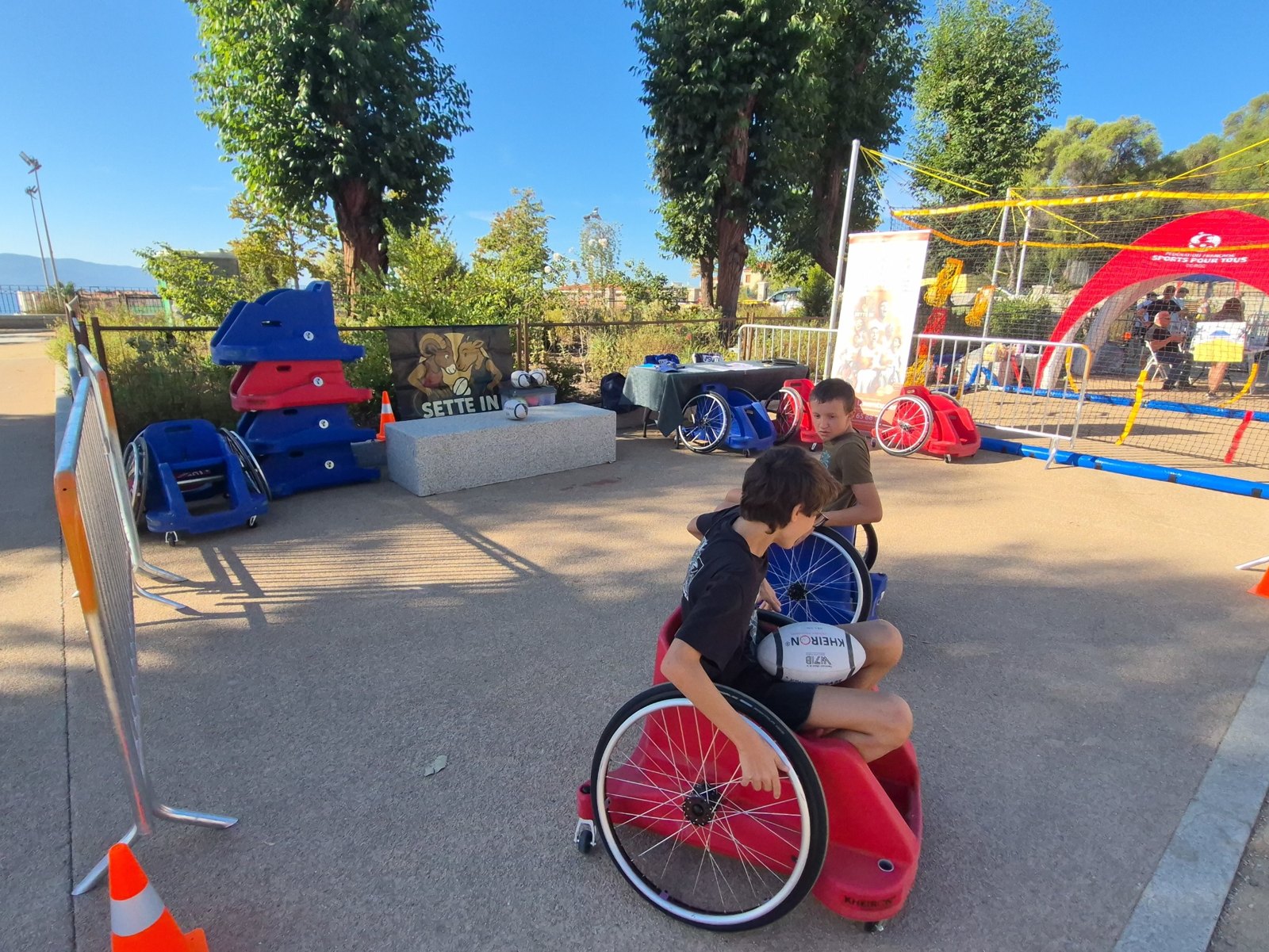 Une jeune participante en fauteuil tient un ballon sur un terrain extérieur.
