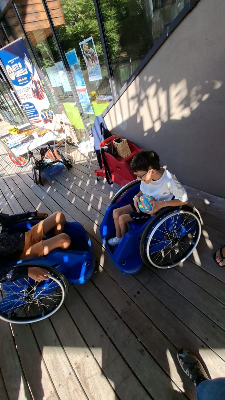Des participants en fauteuil échangent sur une terrasse lors d’un événement.